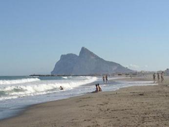 Písečná pláž se skálou Gibraltar v pozadí