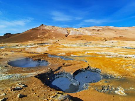 Bahenní tůňky a do červena zbarvená pole solfatár v Námafjall